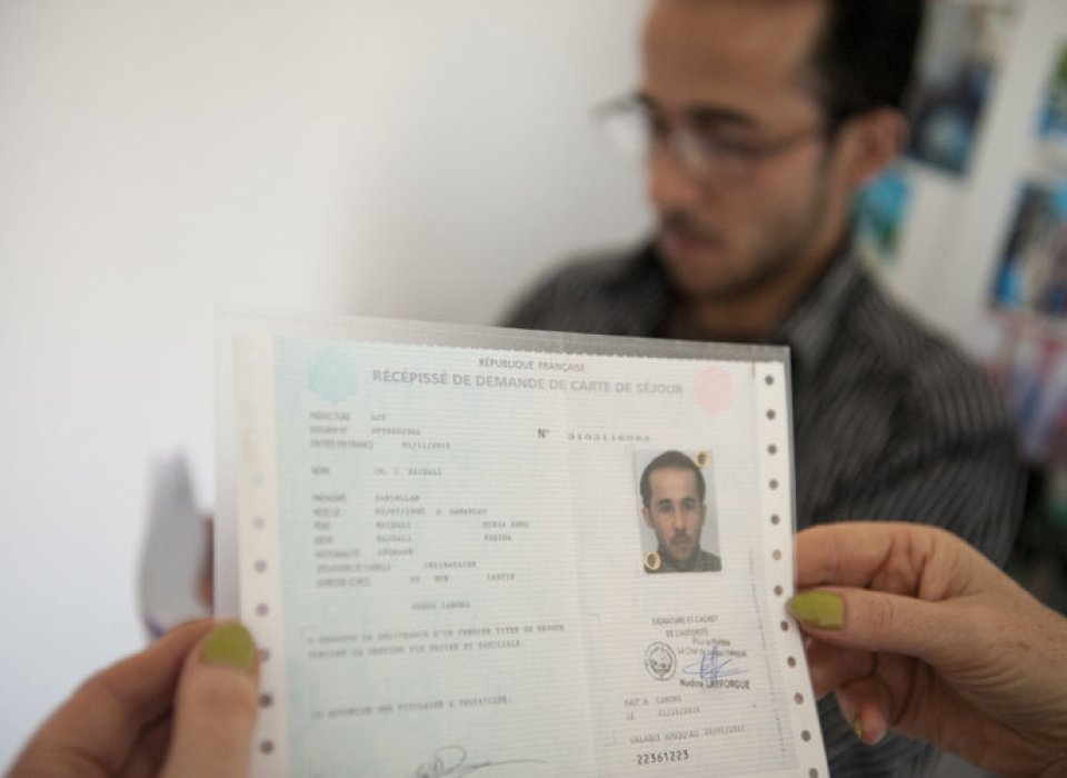 Dans un bureau, un récépissé de demande de titre de séjour enregistrée est remise au demandeur