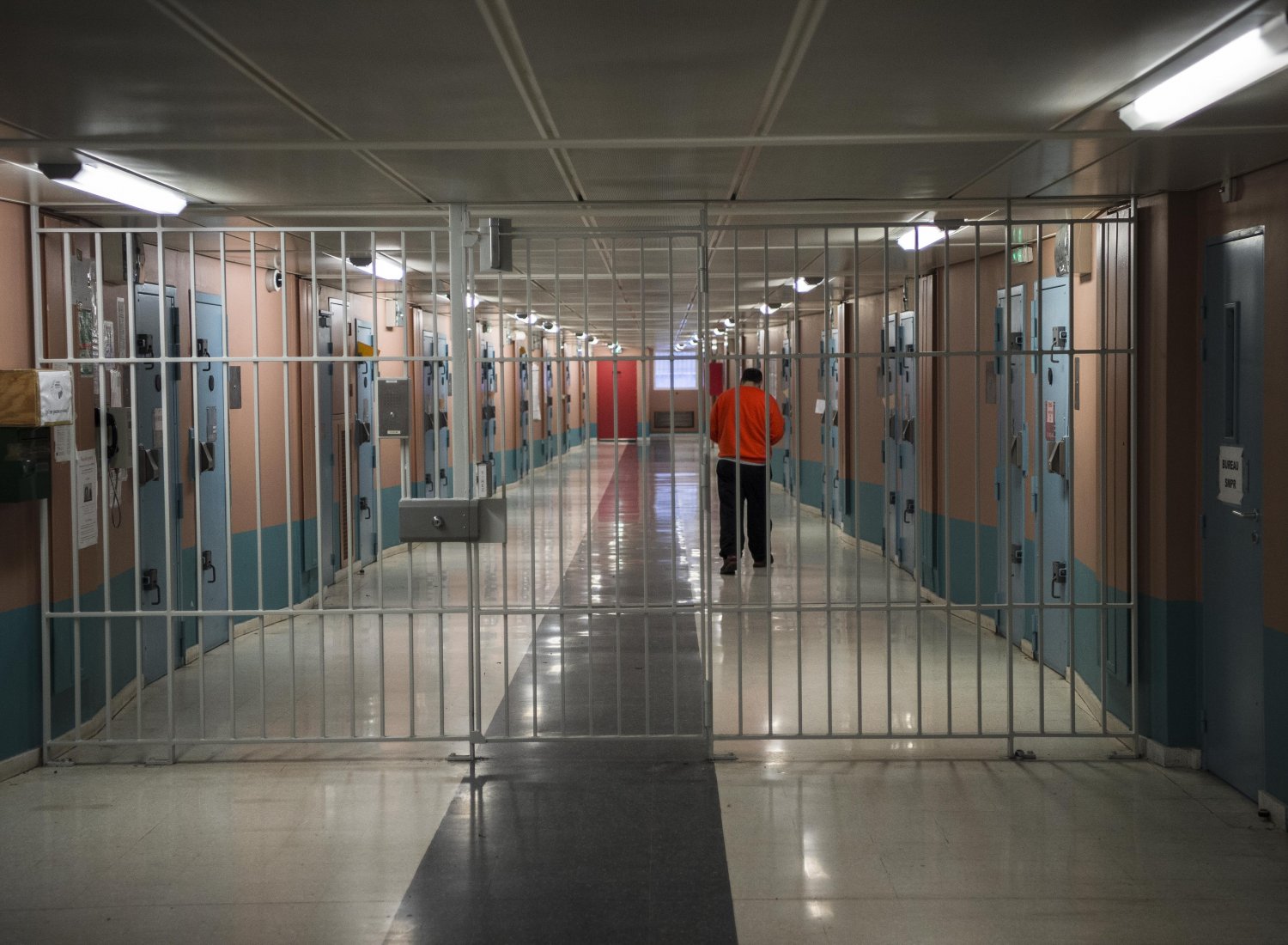 Image d'un couloir de prison avec une grille fermée empêchant le passage.