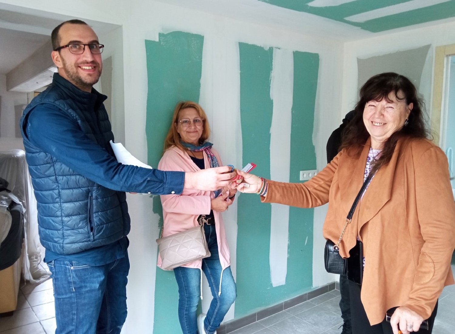 La remise des clefs est un moment important pour les familles. Ici, les 3 acteurs du programme : la famille, la bénévole référente et le coordinateur technique de REH